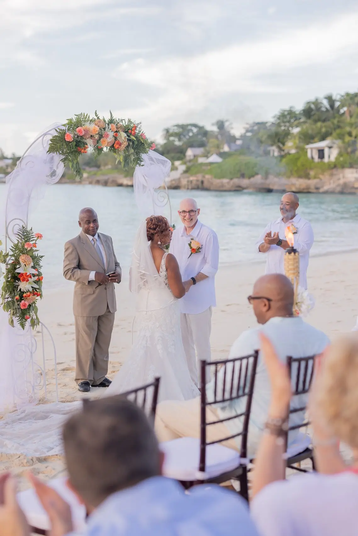A resort beach ceremony with guests seated among purple florals